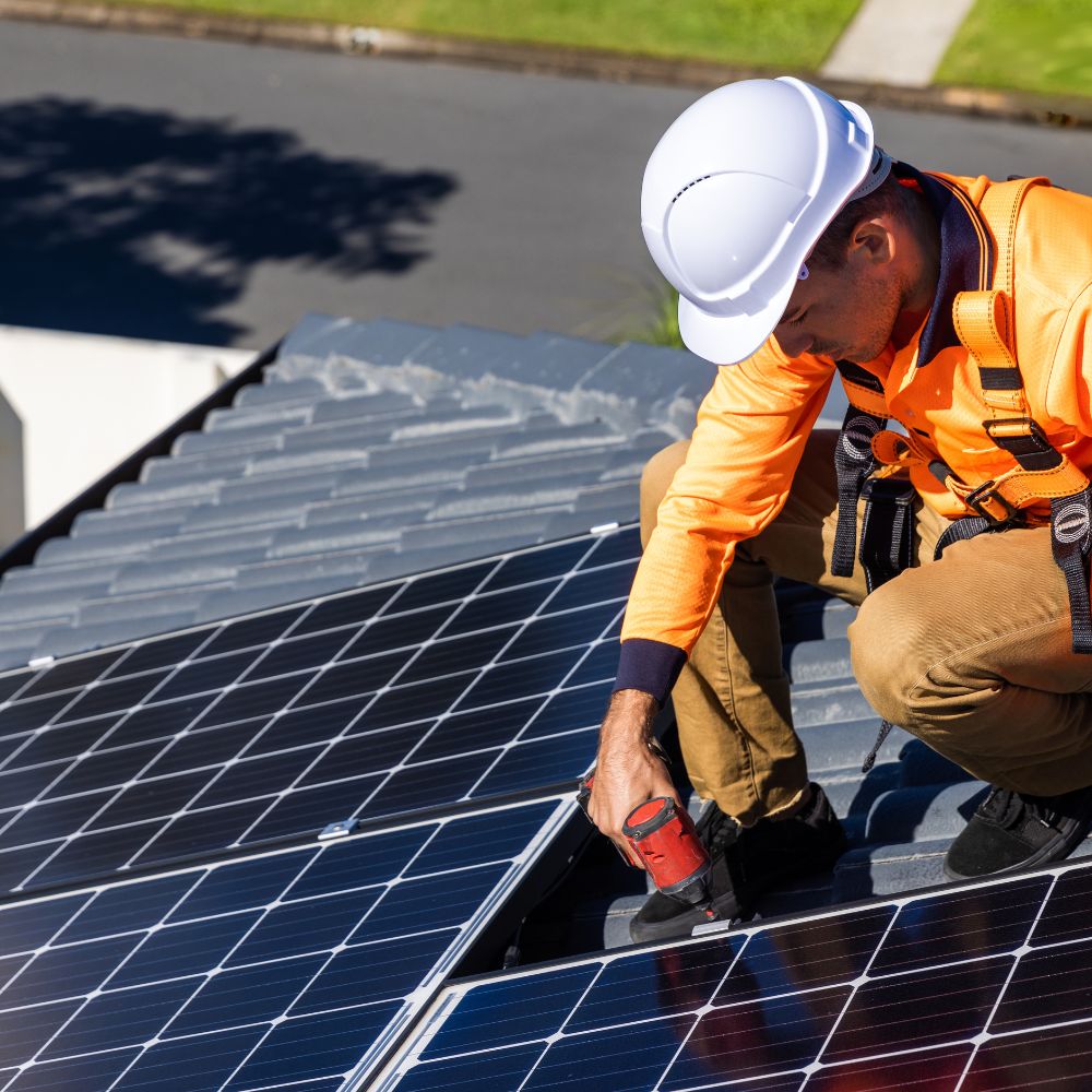 Solar panel technician with drill installing solar panels